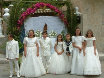 Niños de Primera Comunión posando ante un altar.